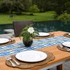 Poolside outdoor wooden dining table set with white plates wicker placemats and organic table runner