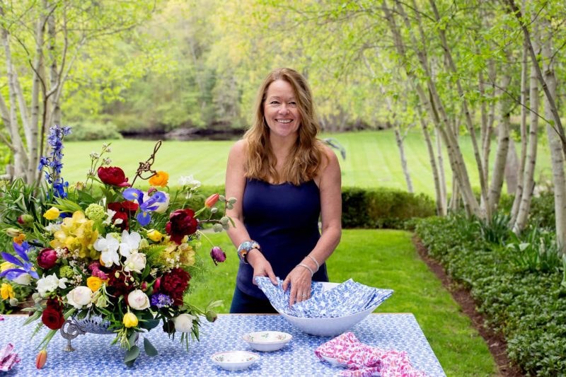 Linda Cabot folding her organic blue napkins outsdie next to a flower arrangement