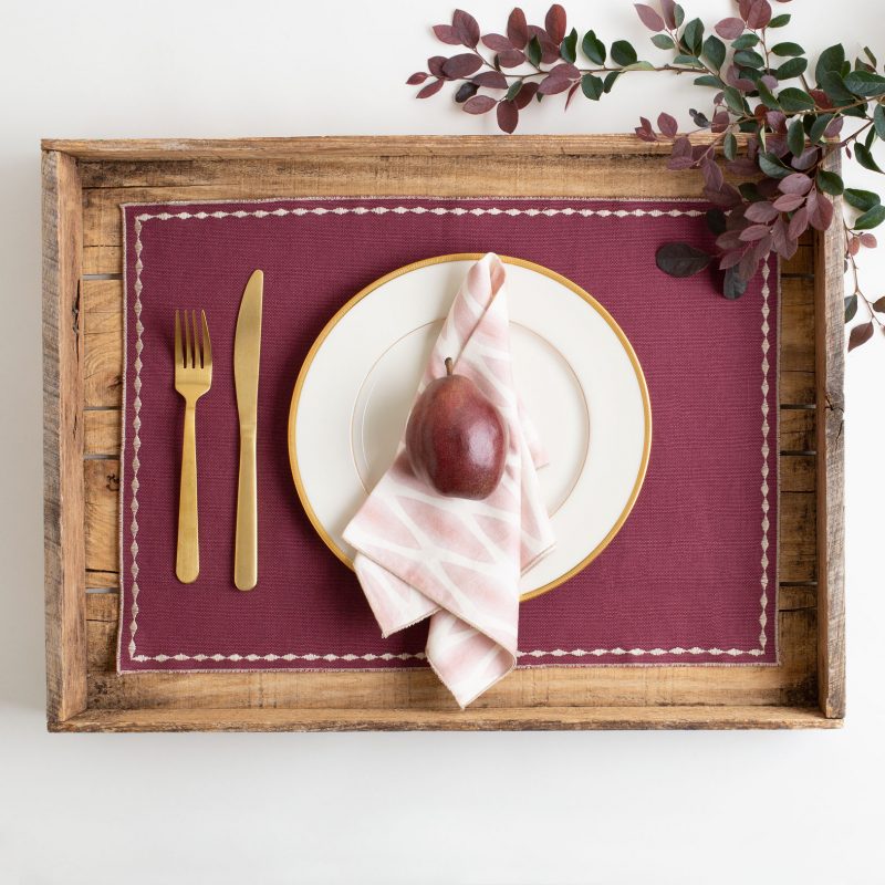 Pink and white patterned organic cotton napkin on solid merlot placemat