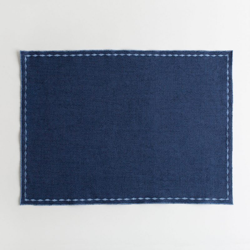 Blue placemat with white decorative stitching